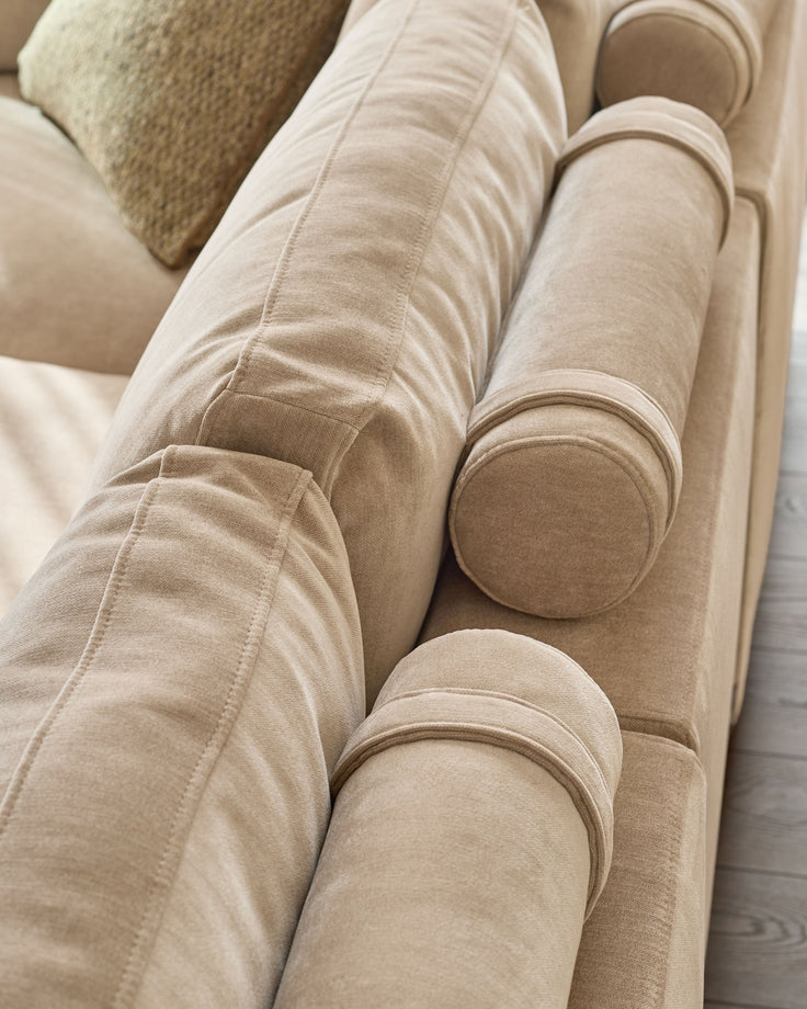 Eden 2-seater sofa in champagne fabric, close-up showing curved armrests and soft upholstery texture.
