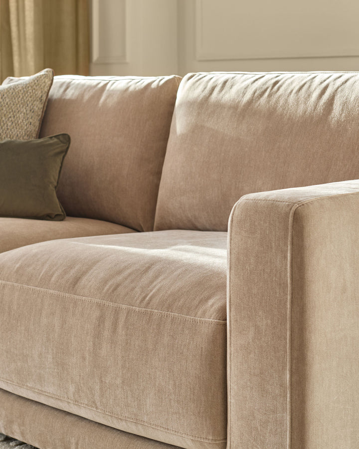 Eden 2-seater sofa in champagne fabric, close-up detail showing cushions, arm, and stitching against neutral interior.