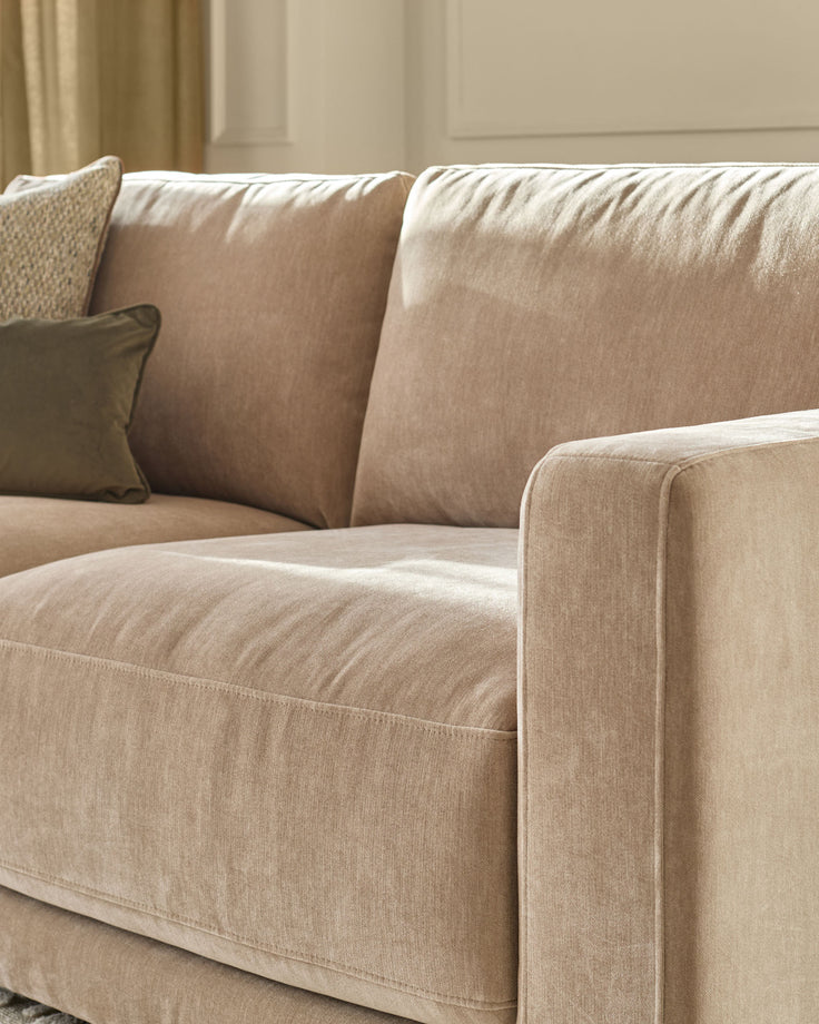 Eden 2-seater sofa in champagne fabric, close-up detail showing cushions, arm, and stitching against neutral interior.