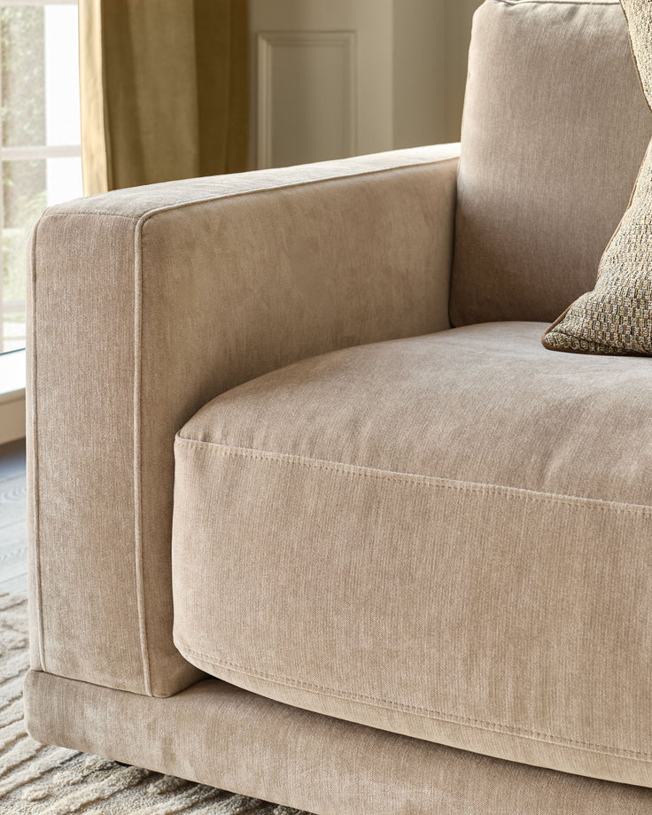 Eden 2-seater sofa in champagne fabric, showing curved armrest and seat detail from side angle.