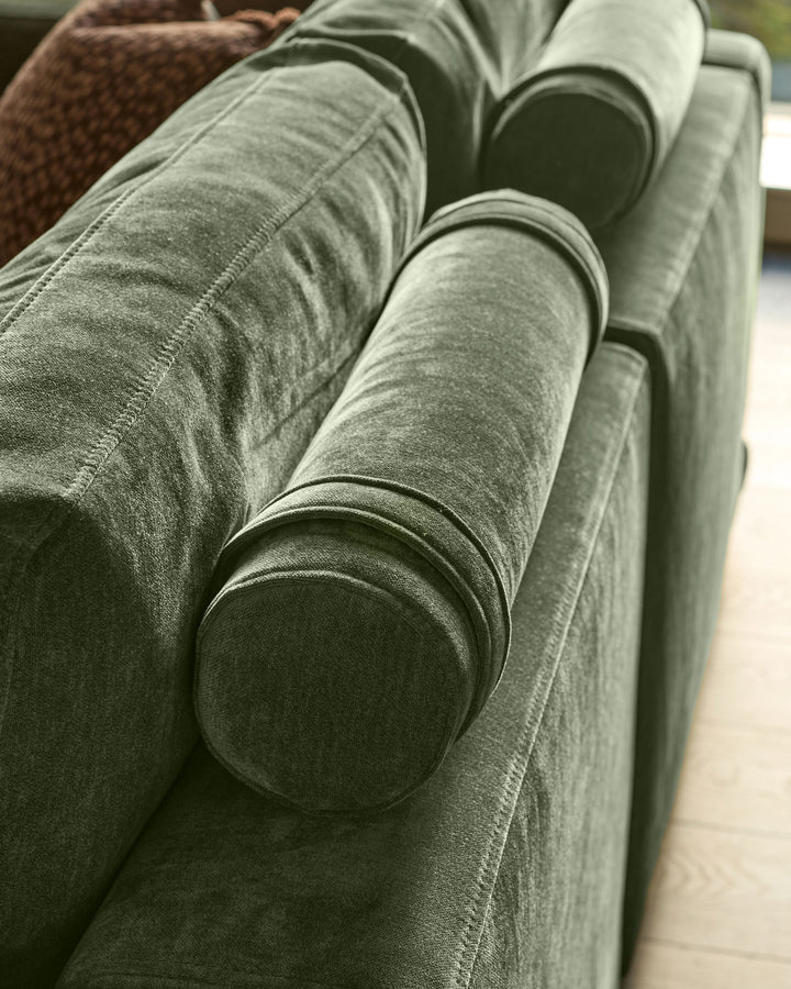 Eden 2-seater sofa in dark green fabric, close-up of rolled arm with contrasting piping detail.
