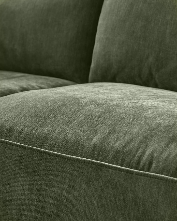 Close-up of dark green fabric sofa showing cushioned seating and backrest with visible stitching detail.