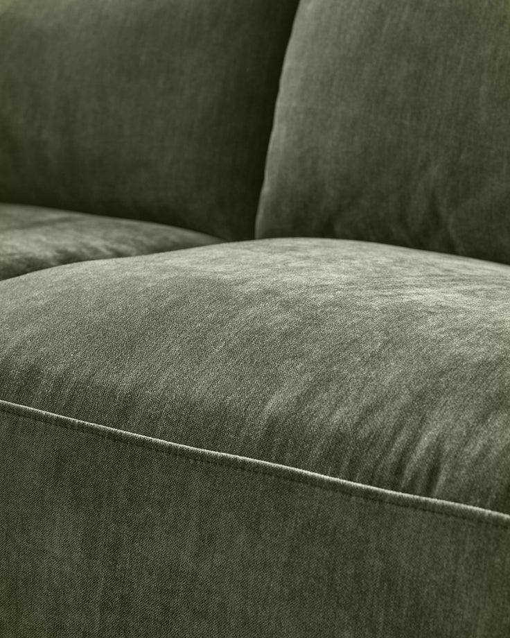 Close-up of dark green fabric sofa showing cushioned seating and backrest with visible stitching detail.
