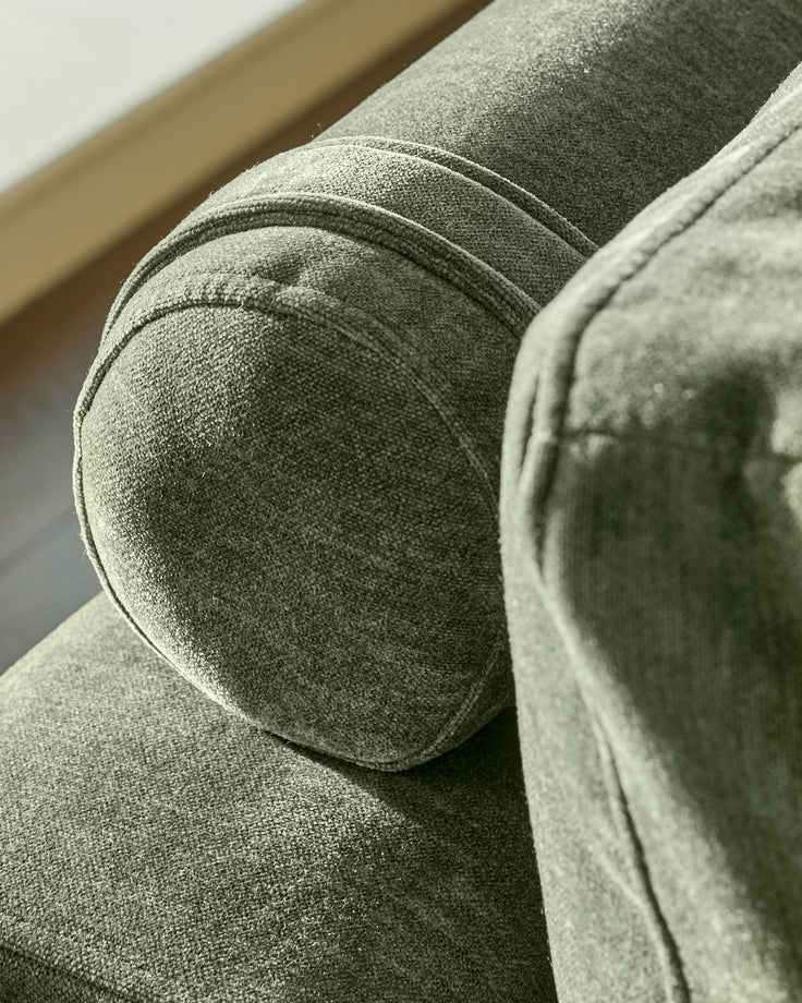 Dark green fabric 2-seater sofa, close-up detail of rounded arm and cushion texture.
