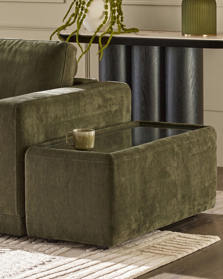 Dark green fabric side table with glass top and storage compartment, positioned next to matching armchair.