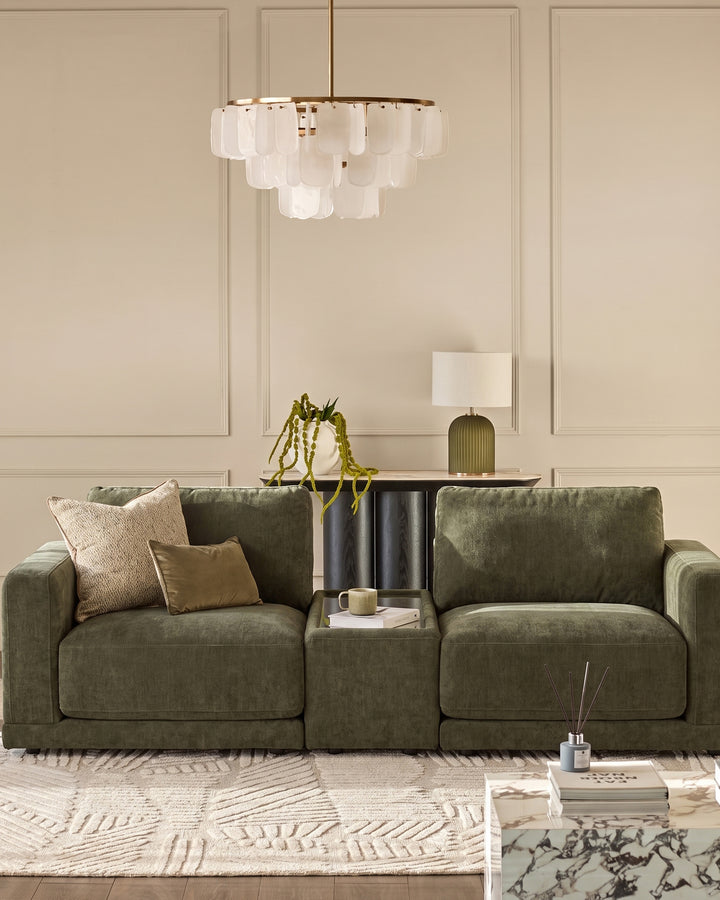 Eden side table module in dark green fabric, positioned between two sage green sectional sofa pieces in a modern living room setting.