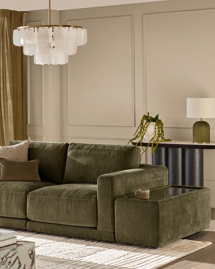 Eden side table module in dark green glass with fabric upholstery, positioned next to olive green sectional sofa in modern living room.