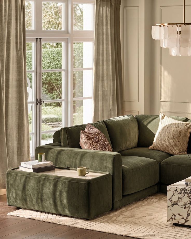 Dark green fabric side table module with glass top, positioned beside matching sectional sofa in bright living room.
