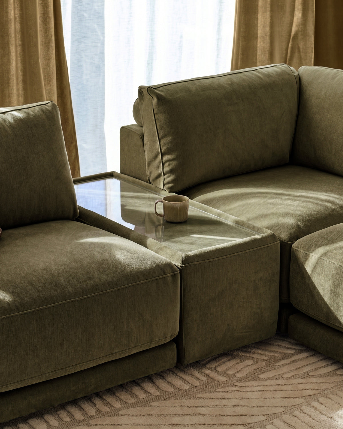 Eden side table module in dark green fabric with glass top, positioned between matching upholstered seating in modern living room setting.