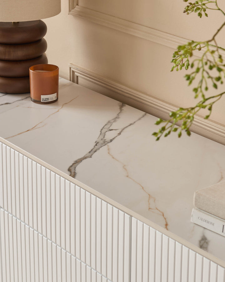 Edie Large Sideboard in natural ceramic with marble-effect top, white ribbed cabinet doors, styled with candle and greenery.