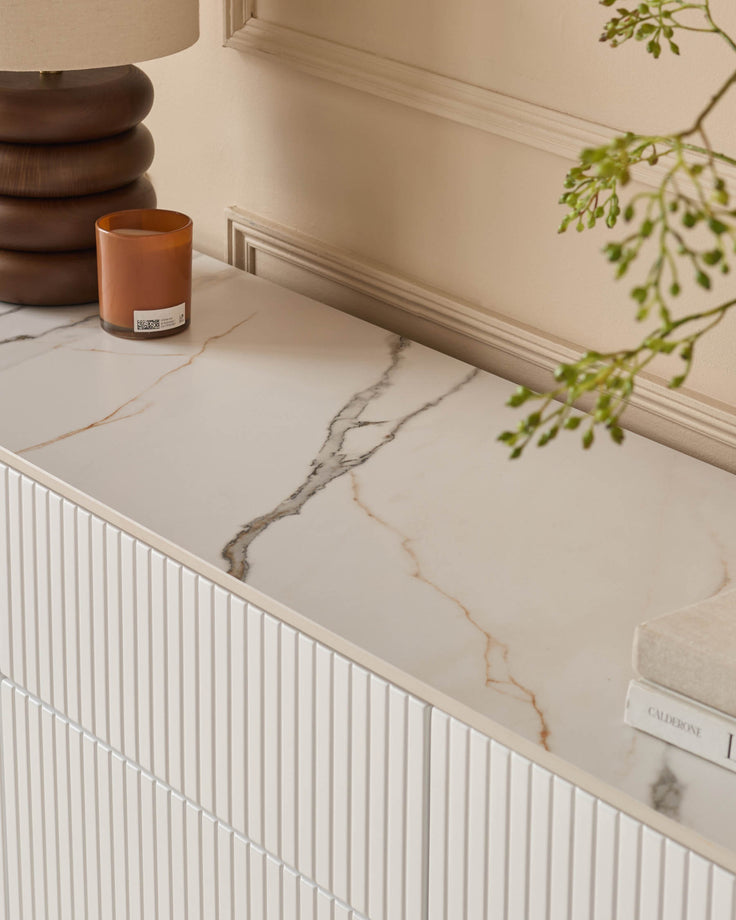 Edie Large Sideboard in natural ceramic with marble-effect top, white ribbed cabinet doors, styled with candle and greenery.