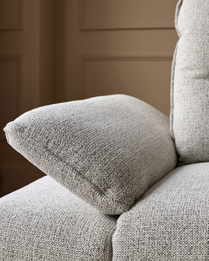 Elio 3-seater sofa in grey fabric, close-up detail showing textured weave and curved armrest.