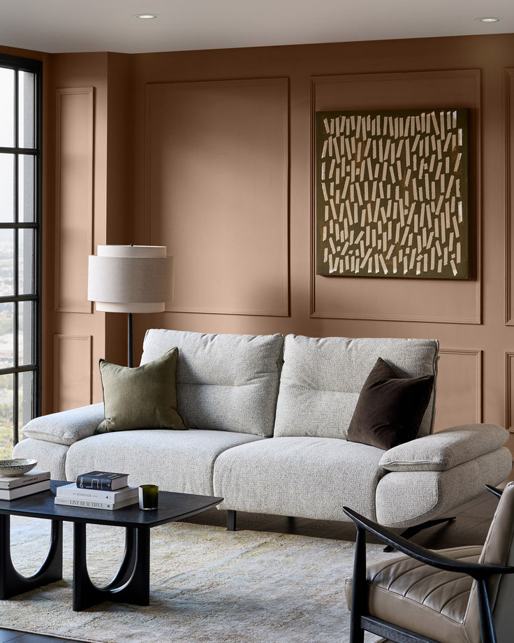 Elio 3-seater sofa in grey fabric with rounded arms, displayed in a warm brown living room setting.