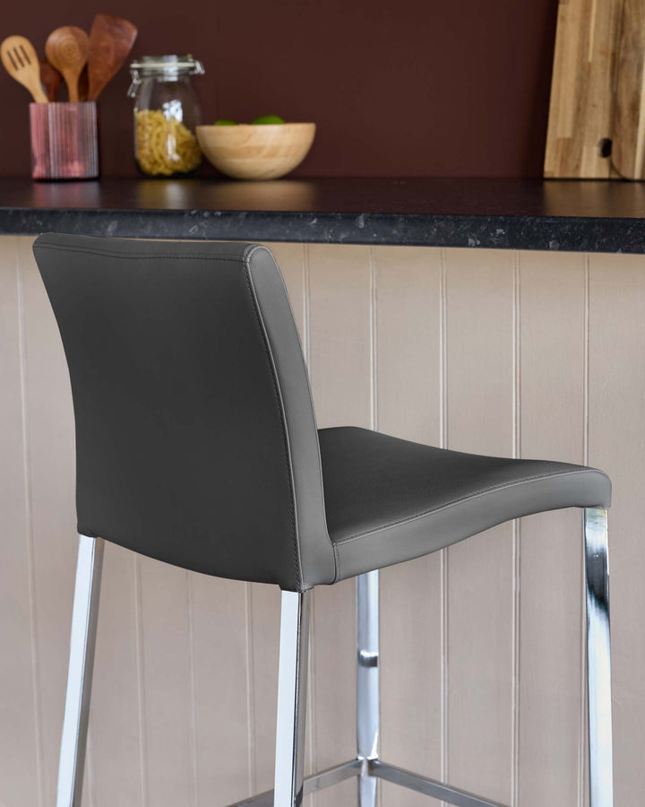 Close-up of a modern, grey faux leather bar stool with chrome legs, positioned at a kitchen counter.