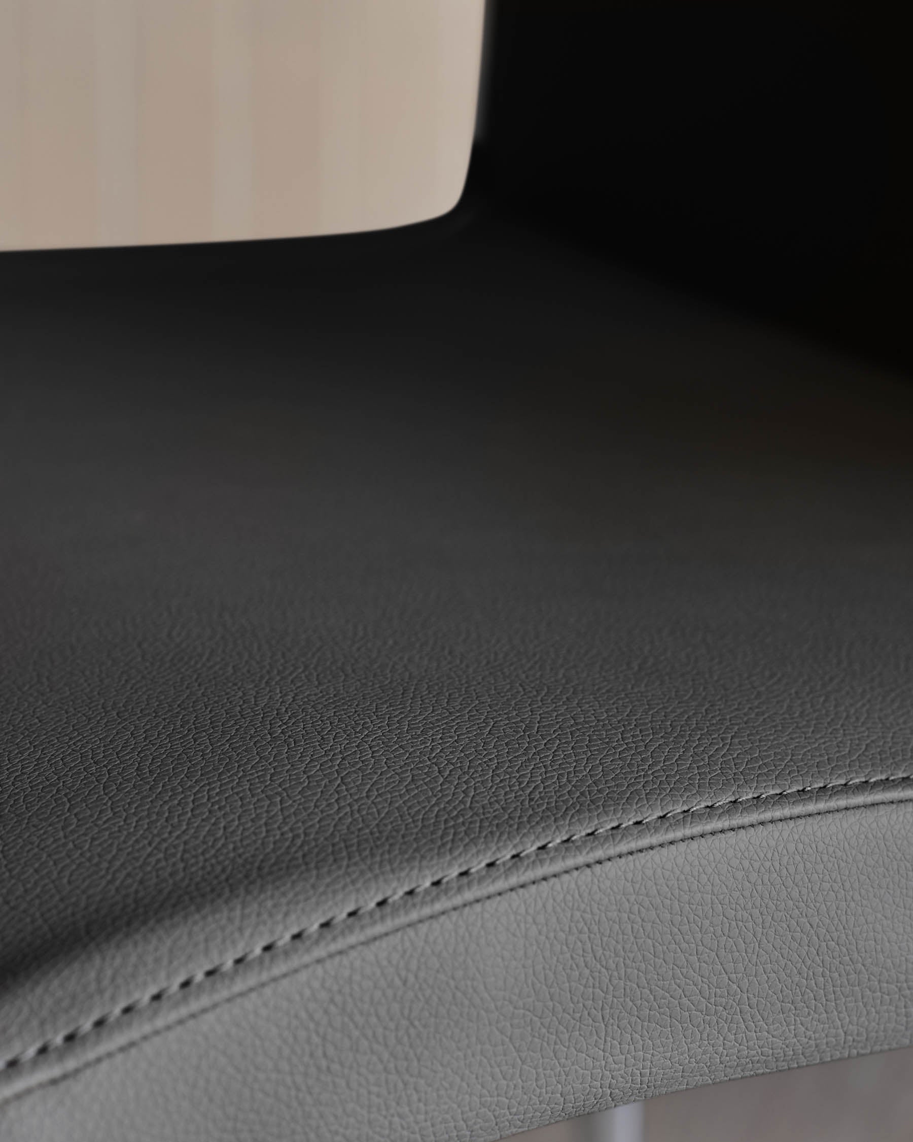 Close-up of a grey leather chair seat with subtle stitch detailing, offering a blend of comfort and modern design.