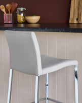 A stylish grey bar stool with a sleek chrome frame, perfect for adding a modern touch to any kitchen or dining area.
