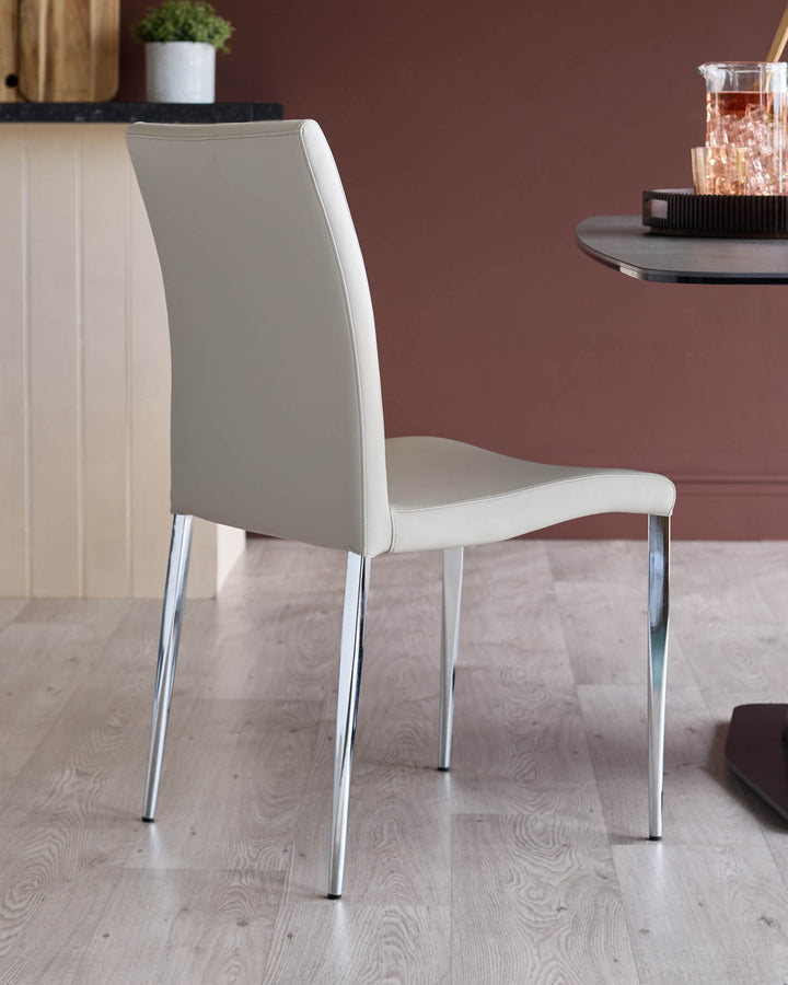 A beige chair with a chrome frame sits on a light wooden floor. Part of a table is on the right side of the shot.