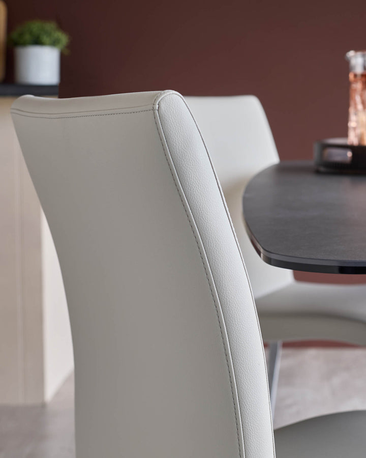 Close up of a stylish grey dining chair with a black table in the background. Modern furniture design.