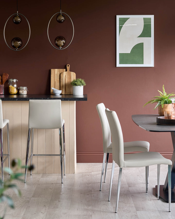 Modern dining area featuring sleek grey chairs, a round table, and bar stools, complemented by stylish lighting and decor.