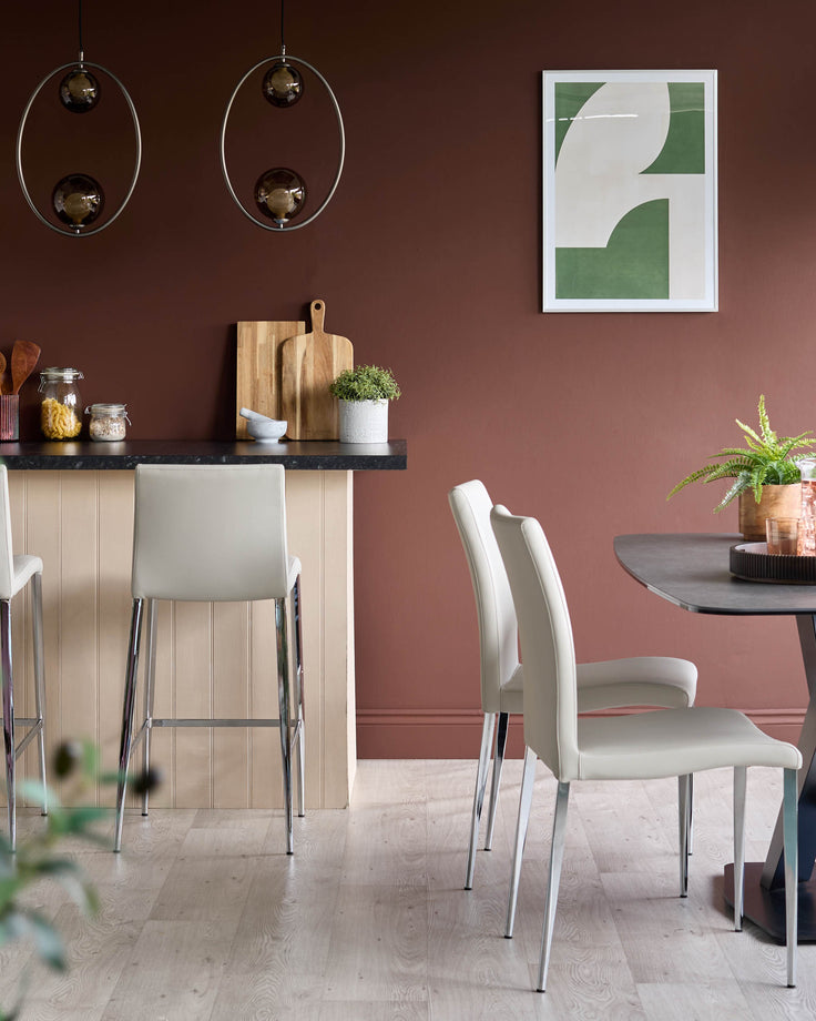 Modern dining area featuring sleek grey chairs, a round table, and bar stools, complemented by stylish lighting and decor.