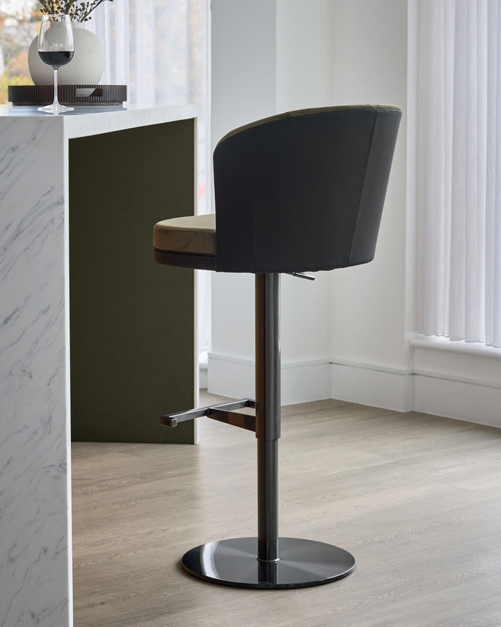 Elodie gas lift bar stool in black velvet with wooden armrest and chrome base, shown at angle in modern interior setting.