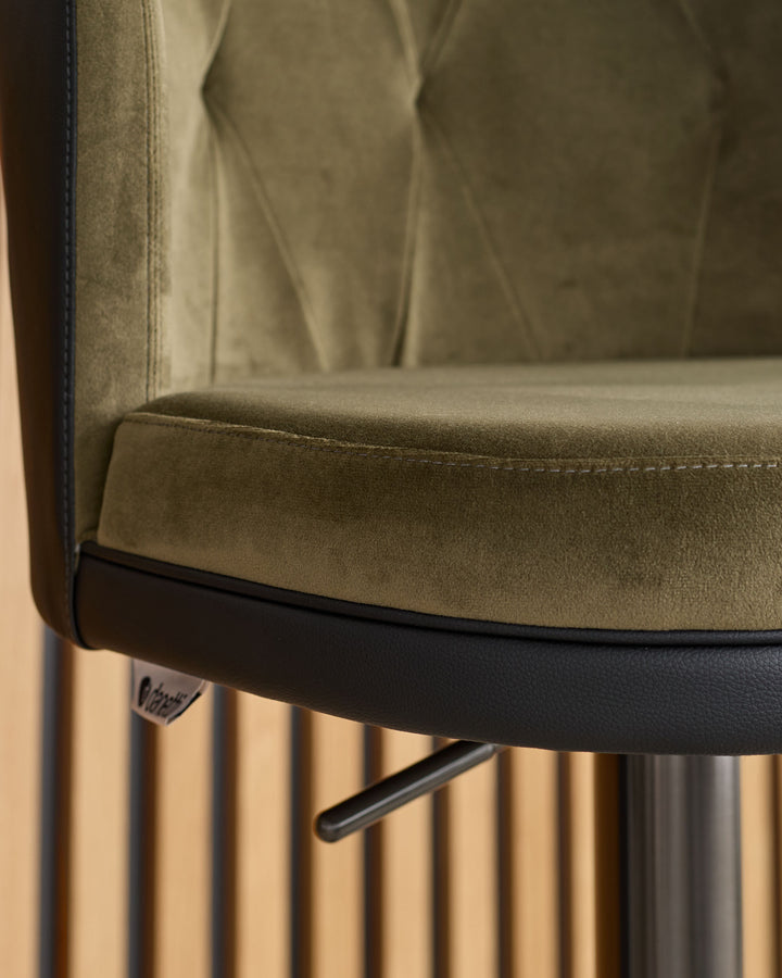 Elodie gas lift bar stool detail showing olive green velvet seat, black base trim, and gas lift mechanism.