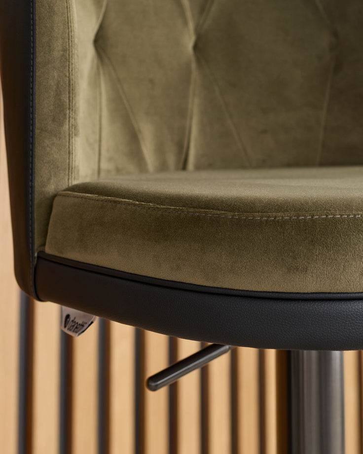 Elodie gas lift bar stool detail showing olive green velvet seat, black base trim, and gas lift mechanism.