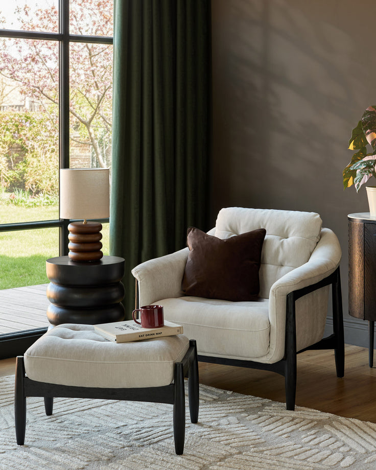 Ember accent chair with footrest in grey fabric, black wooden frame, styled in a bright living room with matching ottoman.