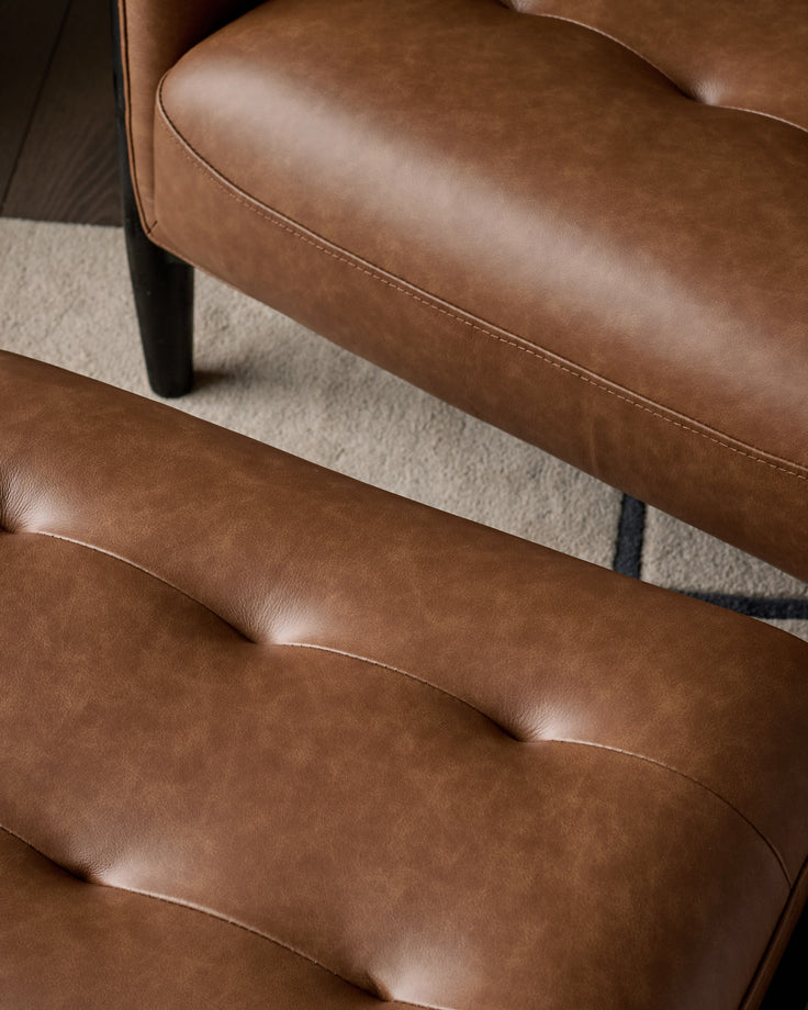 Tan leather accent chair with footrest, showing close-up detail of tufted cushioning and glossy finish.