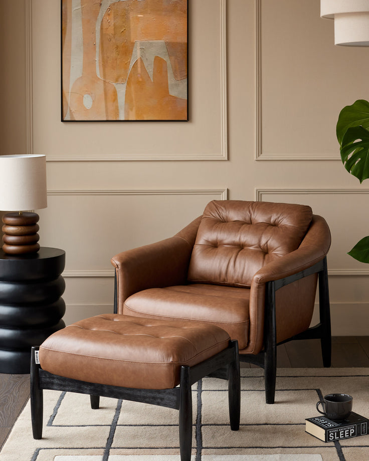 Tan leather accent chair with black wooden frame and matching footrest, displayed in a styled living room setting.