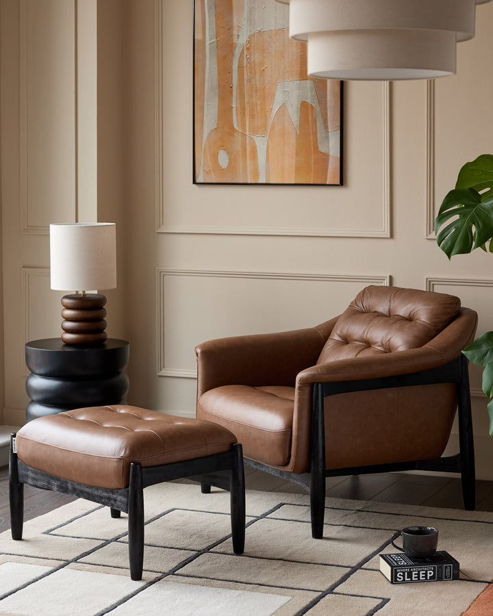 Tan leather accent chair with black wooden frame and matching footrest in modern living room setting.
