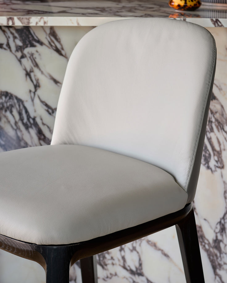 Emerson bar stool with light grey leather seat and backrest, dark grey wooden legs, shown at an angle.