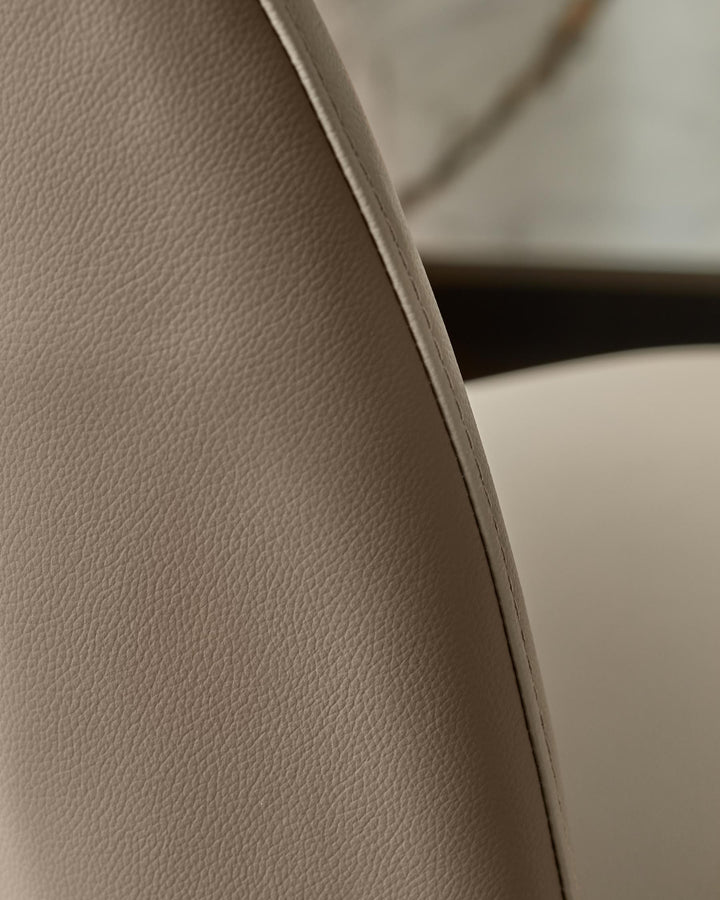 Close-up of a stylish beige chair with textured leather upholstery and refined stitching, perfect for a modern home.