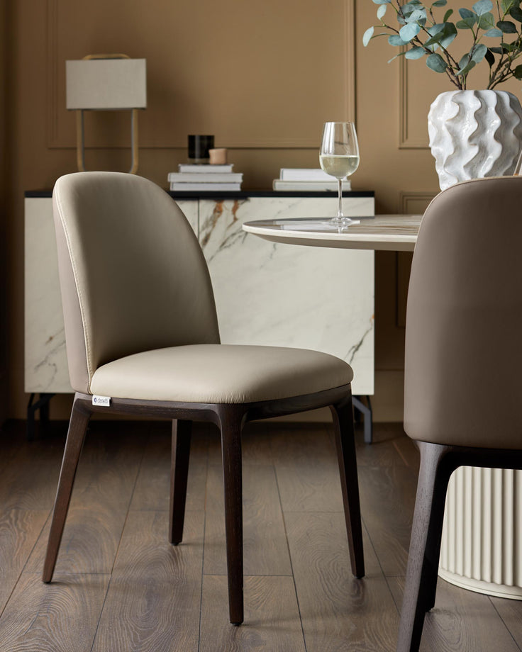 Contemporary dining set with stylish chairs featuring wooden frames and neutral upholstery, complemented by a marble-topped table.