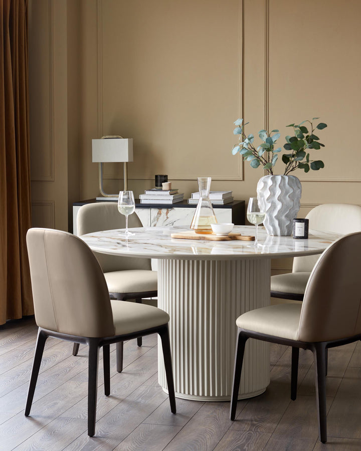 A modern dining table with marble top and fluted base, surrounded by four chairs with dark wooden legs.