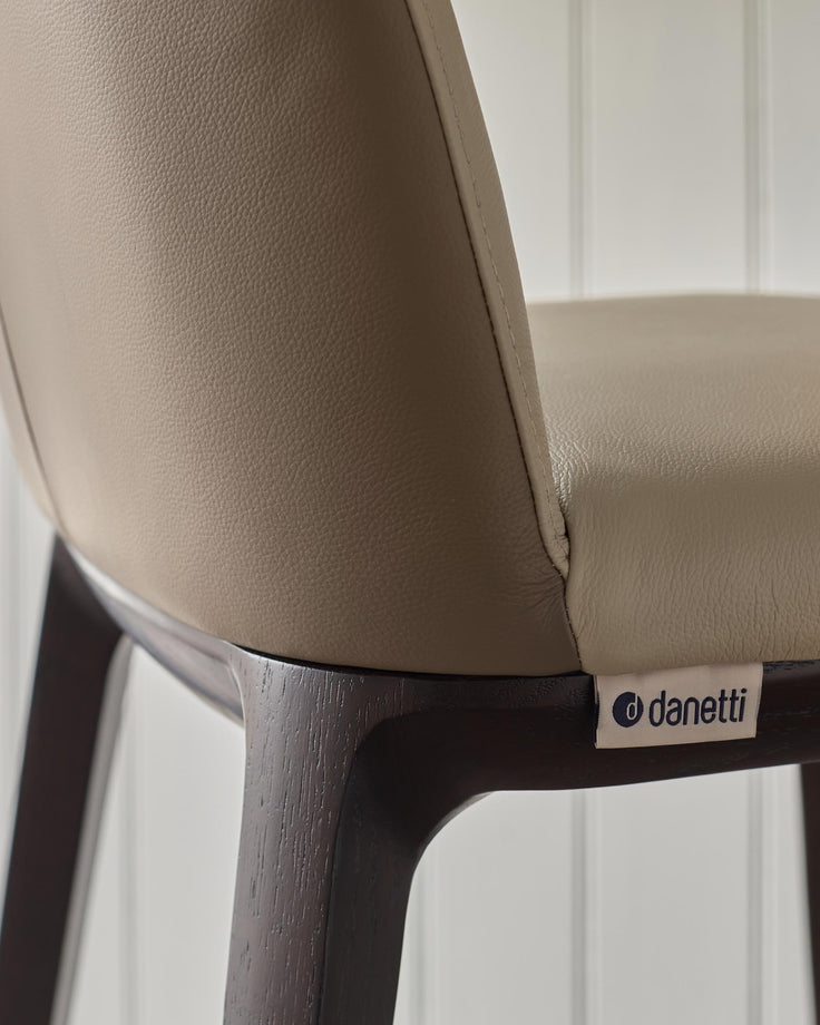Close-up of a modern 'Danetti' chair with a grey leather seat and a dark wooden frame.