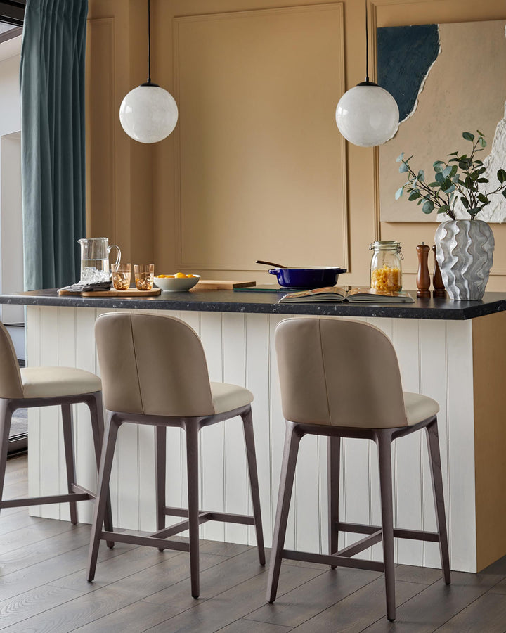 Kitchen with bar stools at island, marble countertop, pendant lighting, decor. Modern furniture design.