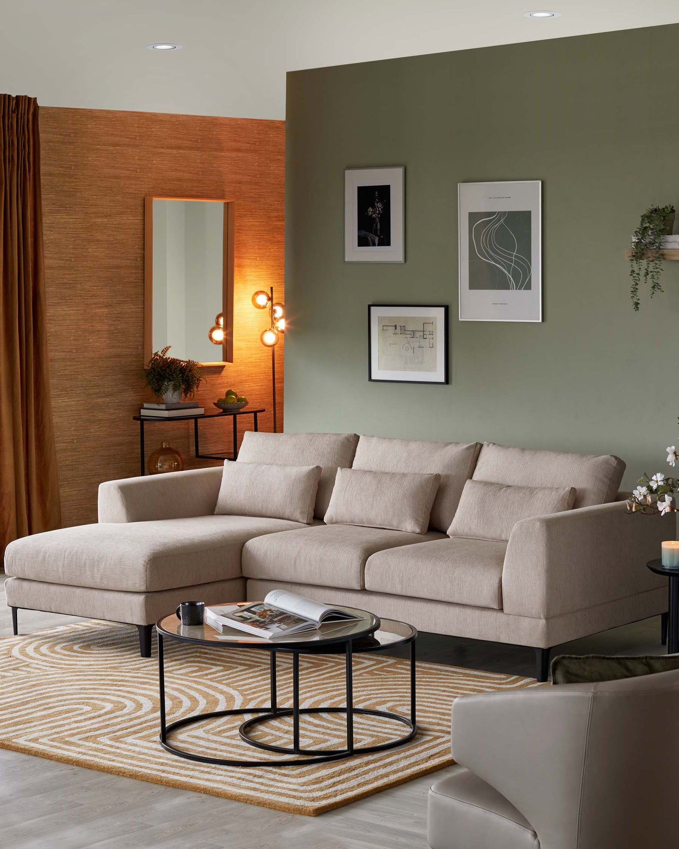 L-shaped beige fabric sectional sofa with clean lines and comfortable cushions, a rectangular wooden side table with a bottom shelf, and a pair of round black nesting coffee tables with glass tops on a patterned beige and white area rug.