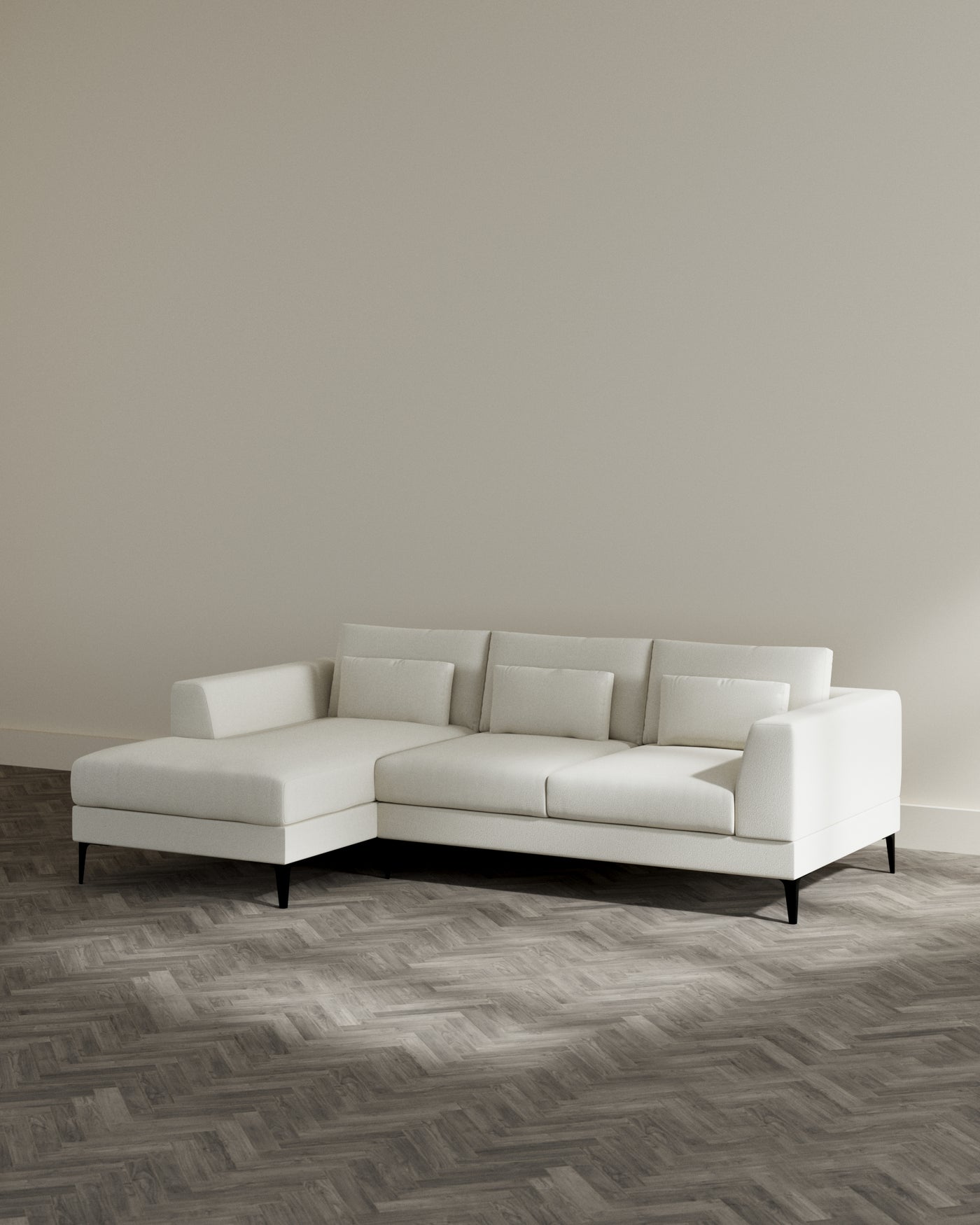 Modern light beige corner sectional sofa with clean lines, plush cushions, and tapered dark wooden legs on a herringbone patterned wooden floor.