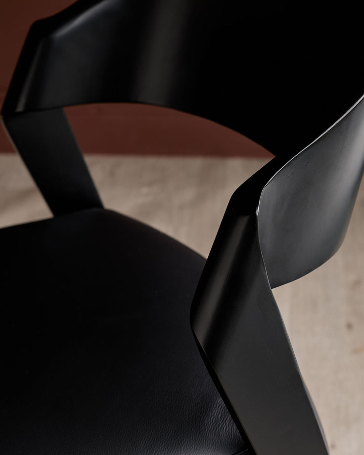 Enzo dining chair in black real leather, close-up of curved backrest and armrest detail