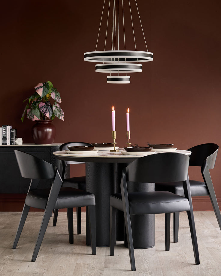 Enzo dining chair in black leather, shown in modern dining room setting at round table with candles and place settings.