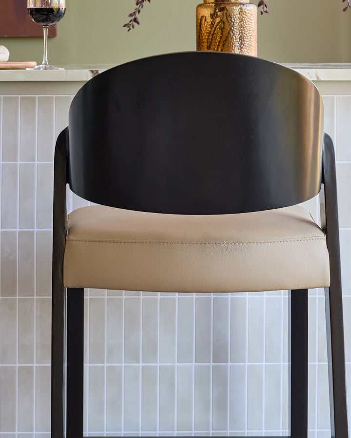 Enzo bar stool in natural leather with black curved backrest and metal frame, front view.