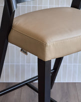 Enzo bar stool in natural leather with black metal frame, shown in close-up detail of seat and legs.