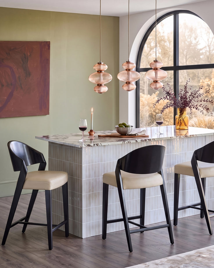 Enzo bar stool in natural leather with black wooden frame, shown at marble counter in modern dining space.