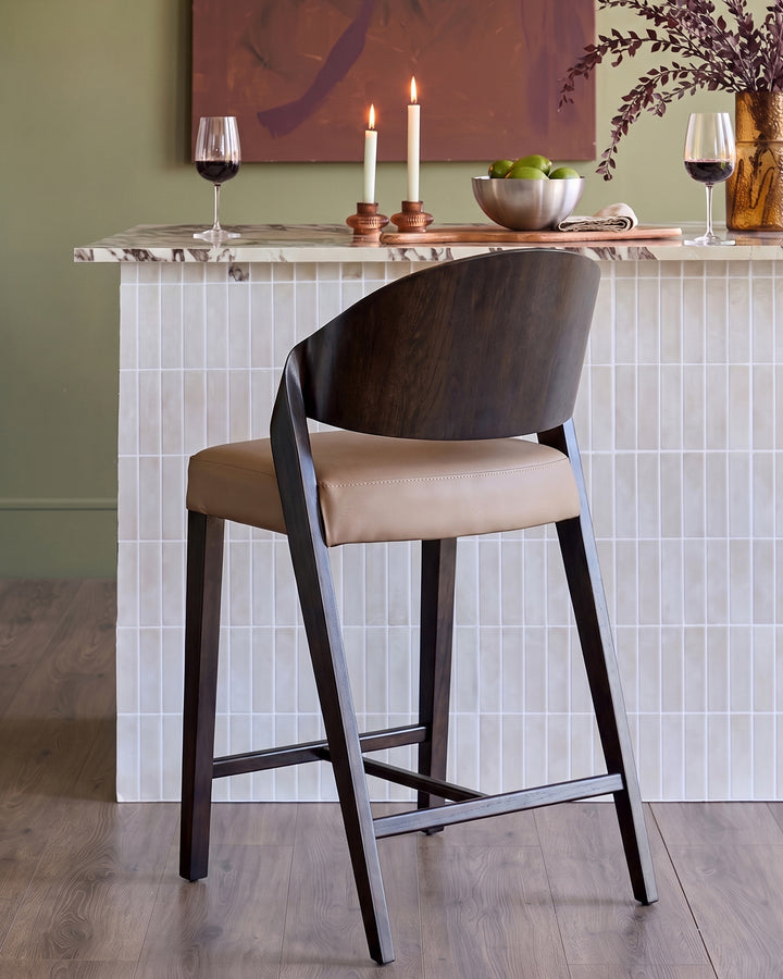 Enzo bar stool in mocha leather with dark wood frame, shown at white tile counter with wine glasses and candles.