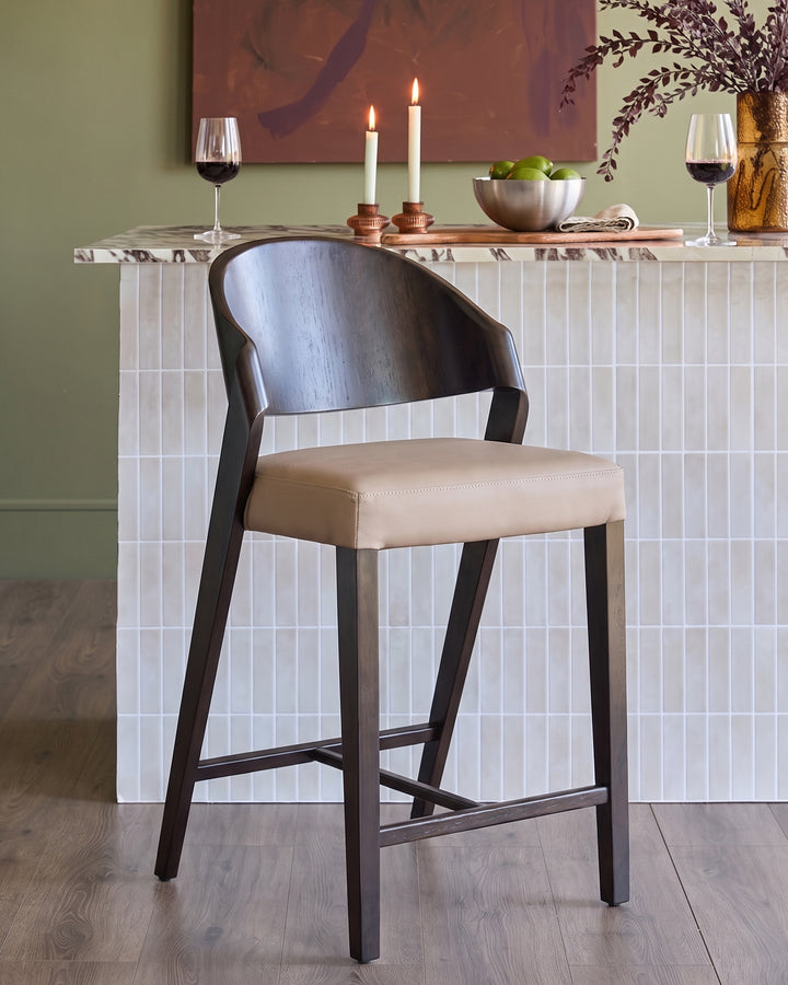 Enzo bar stool in mocha leather with dark wood frame, shown at white marble counter with wine glasses and candles.