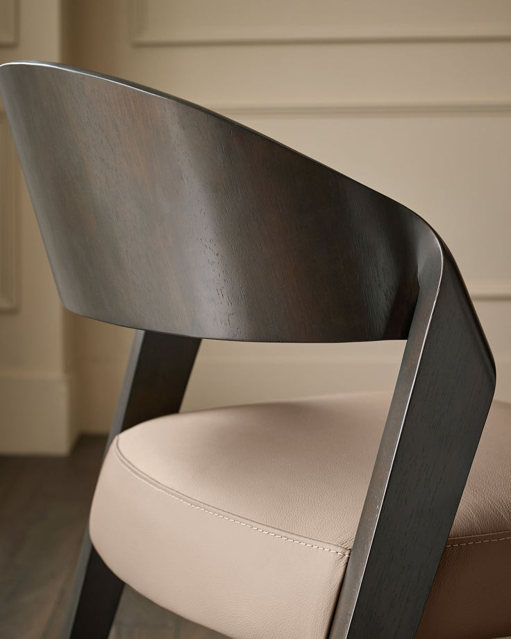Dark wood curved backrest with cream leather seat, angled side view showing modern chair design.