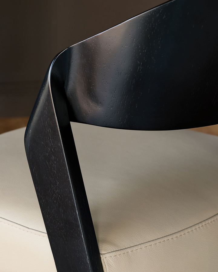 Enzo dining chair close-up showing black wooden frame and natural leather seat from side angle.