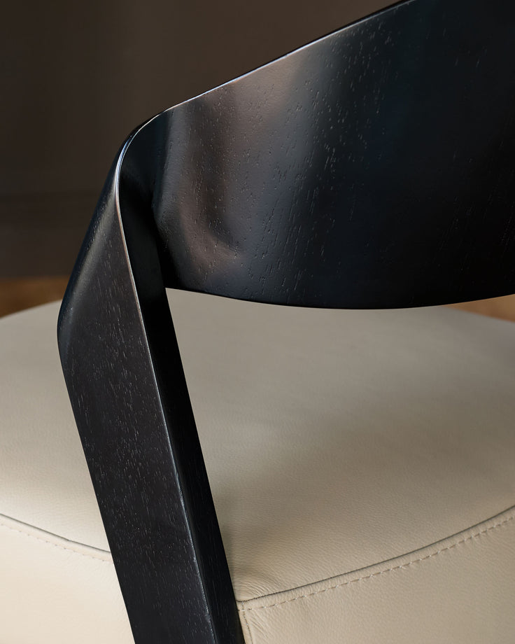 Enzo dining chair close-up showing black wooden frame and natural leather seat from side angle.
