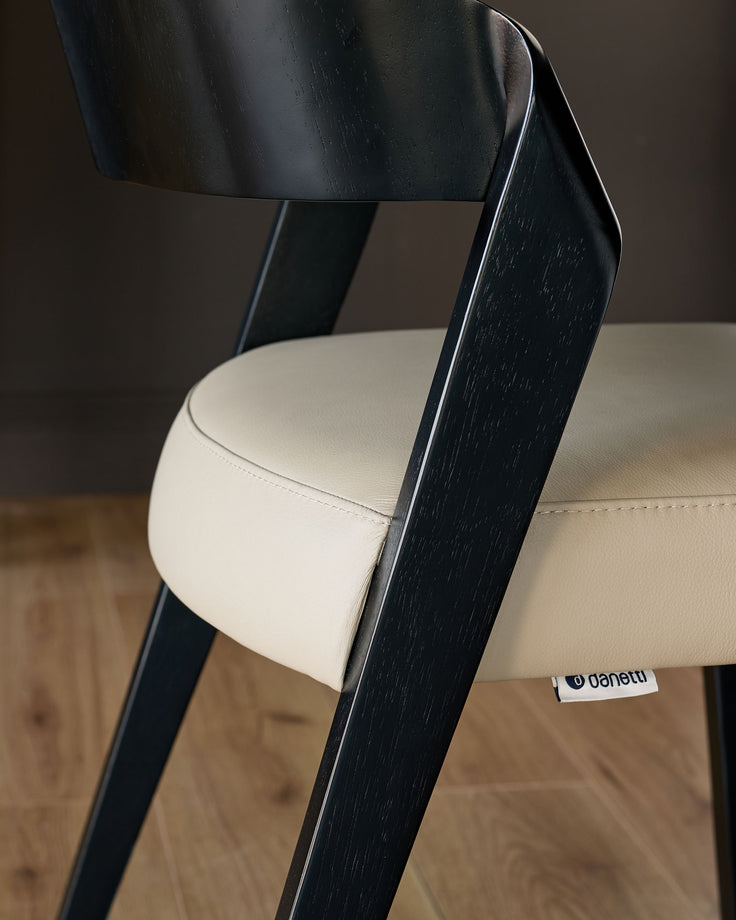 Enzo dining chair with black wood frame and natural leather seat, angled side view.